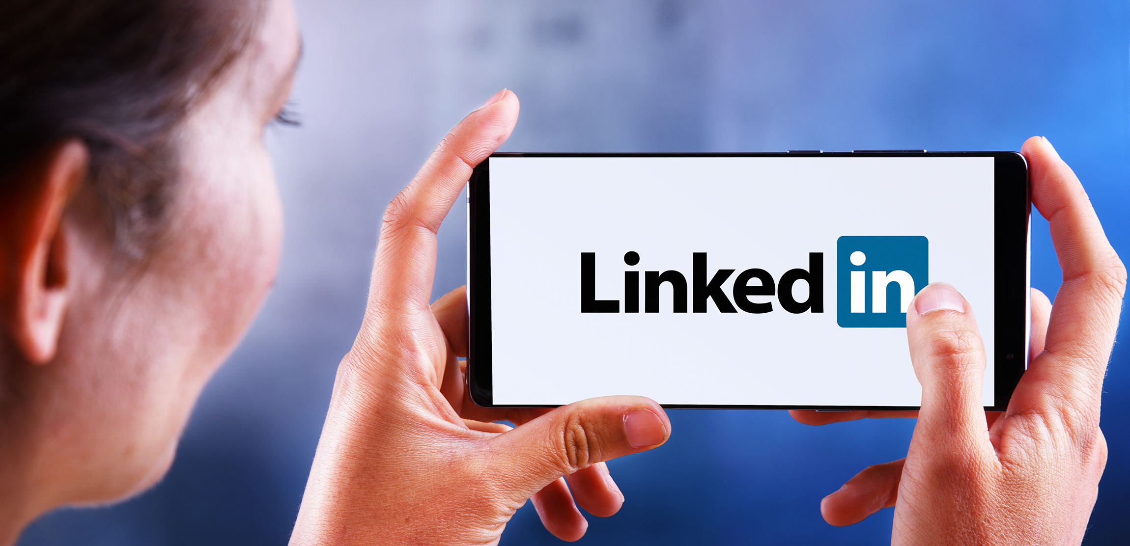 woman holding smartphone displaying logo of linkedin